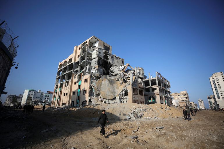 Palestinians walk near a destroyed building of Islamic University, following an Israeli ground operation, amid the ongoing conflict between Israel and Hamas, in Gaza City, February 10, 2024. REUTERS/Stringer